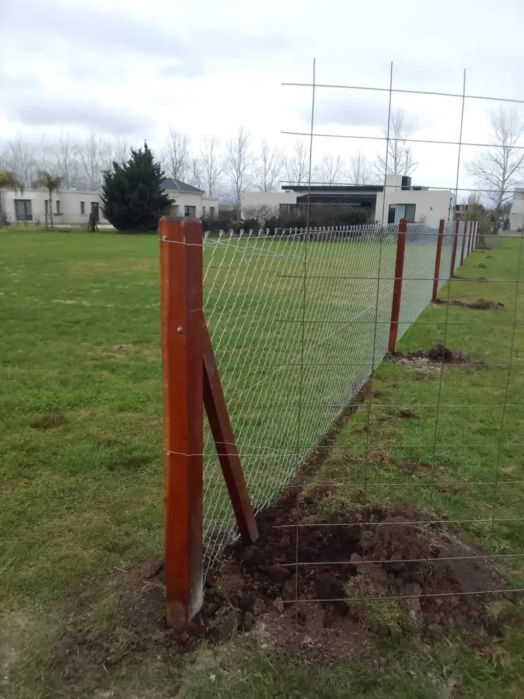 Detalle de poste esquinero de madera con puntal en cerramiento de terreno